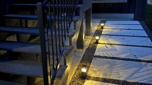 A staircase with a metal railing and steps leading to a covered area with a swing seat. - Luxury Lakefront Living in Marble Falls: Pool, Private Dock & Endless Views! (Marble Falls)