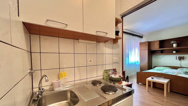 A compact kitchen with a stainless steel sink, a small stove, and a wooden countertop. - Apartment Marija 6 (Crikvenica)