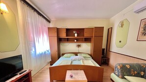 A room with a bed, a TV, a wooden table, and a sofa. - Apartment Marija 6 (Crikvenica)
