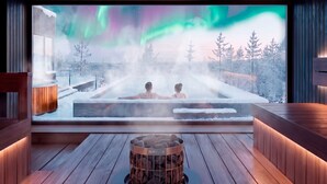 A spa room with a large window, a hot tub, and a stone fireplace. - SkyView Igloo Resort & Spa (Rovaniemi)