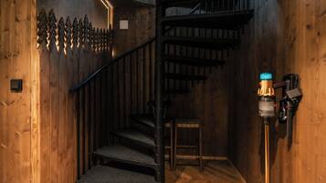 A wooden staircase with a metal railing, a small wooden table, and a wall-mounted light fixture.