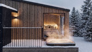 A wooden cabin with a hot tub, a bed, and a view of snow-covered trees. - SkyView Igloo Resort & Spa (Rovaniemi)