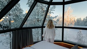 A bedroom with a large bed, a window, and a view of snow-covered trees. - SkyView Igloo Resort & Spa (Rovaniemi)