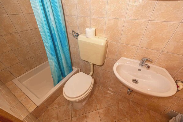 A bathroom with a bathtub, toilet, and sink. - Studio Mistral 5 (Crikvenica)