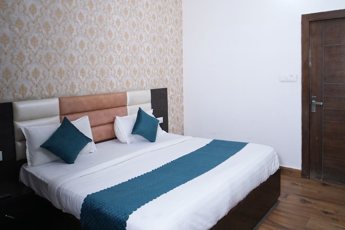 Une chambre à coucher avec un lit, un ventilateur de plafond, une porte en bois et un papier peint à motifs.