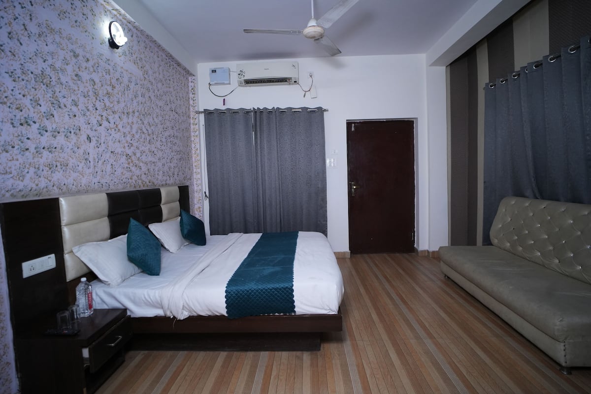 Une chambre d’hôtel équipée d’un lit, d’un canapé, d’un ventilateur de plafond, d’un appareil de climatisation et d’une porte.