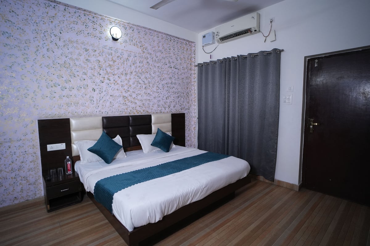 Une chambre à coucher comprenant un lit, des tables de chevet, un climatiseur fixé au mur et une porte.