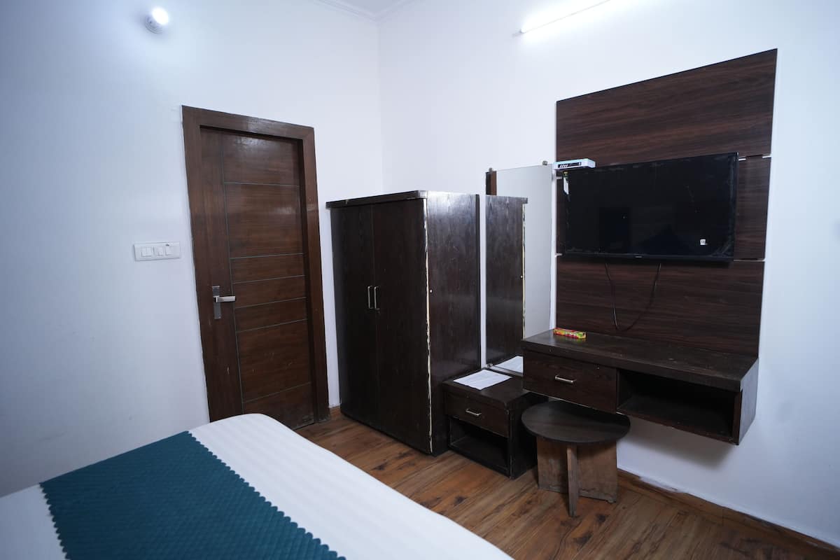 Une chambre à coucher comprenant un lit, une armoire, un bureau et un téléviseur fixé au mur.