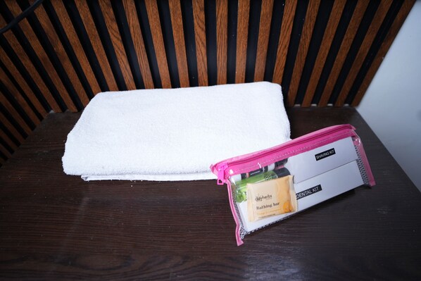 A white towel and a pink toiletry bag on a wooden chair.
