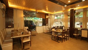 Un restaurant avec un plafond en bois, des tables et des chaises, et une voiture garée devant.