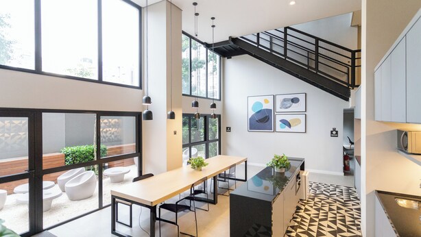 Une cuisine moderne dotée d’un îlot central, d’un escalier et de grandes fenêtres.