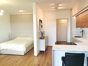 A modern bedroom with a bed, a small desk, and a mirror.