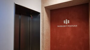 An elevator with a red wall and a sign that reads 'NUSLESKÝ PIVOVAR'. - Free Parking, Center Location, Nuslesky Pivovar Sunset Balcony Home (Prague)