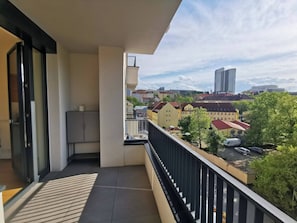 A balcony with a view of a cityscape, including buildings and a tall skyscraper.