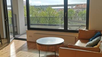 Un salon spacieux avec une grande fenêtre, une table ronde et un canapé en cuir.