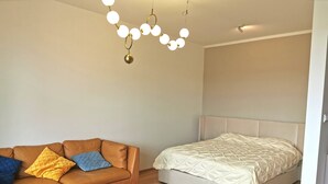 A bedroom with a bed, a sofa, and a round wooden table. - Free Parking, Center Location, Nuslesky Pivovar Sunset Balcony Home (Prague)