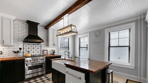 A modern kitchen with a central island, stainless steel appliances, and a wooden countertop.