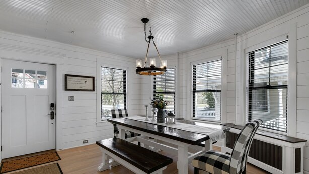A dining area with a wooden bench, a table, and a chandelier.