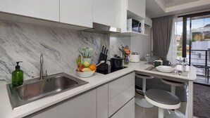 A modern kitchen with a marble backsplash, stainless steel sink, and a dining area with a small table and two chairs. - Chill & Relax Stay at Rawai Condo 311 (Rawai)