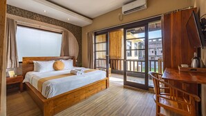 A hotel room with a wooden bed, a desk, and a view of the outside. - Cove Kavana (Tibubeneng)