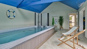 A spa area with a hot tub, a lounge chair, and a ceiling fan.