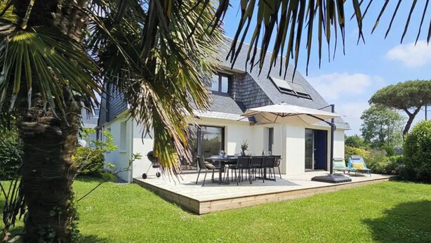 A modern house with a patio, a dining area, and a large umbrella.