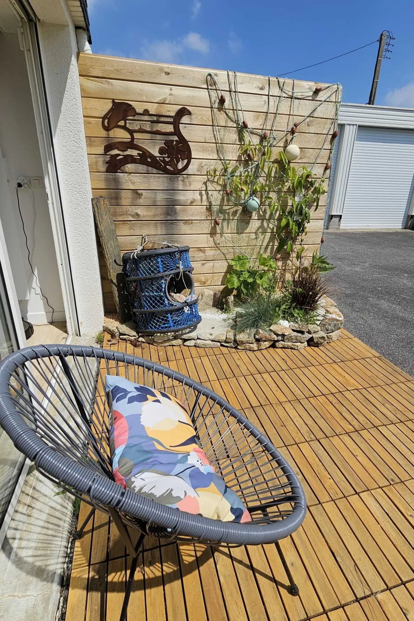 A wooden deck with a wicker chair and a blue birdcage.