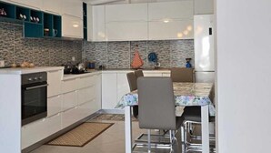 Une cuisine moderne avec des meubles blancs, un pare-feu en carreaux et un coin repas comprenant une table et des chaises.