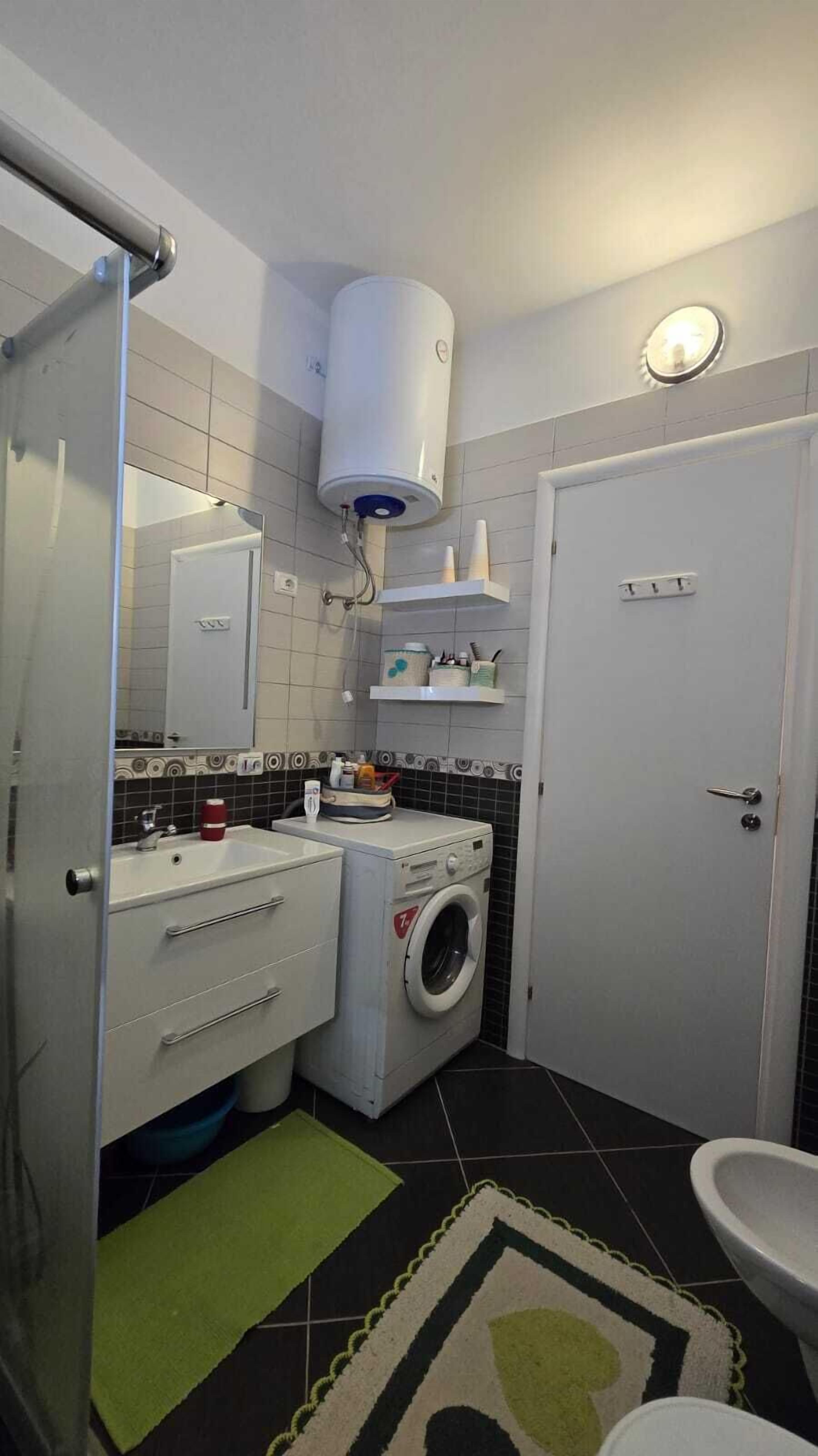 Ein kleines Badezimmer mit Waschmaschine, Waschbecken, Toilette und Handtuchhalter.