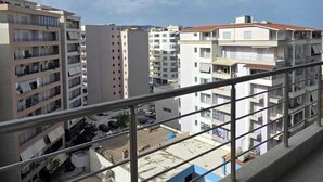 Un balcon donnant sur un quartier résidentiel, avec des immeubles à plusieurs étages et un ciel dégagé.