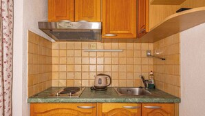 A compact kitchen with wooden cabinets, a gas stove, a kettle, and a sink. - Studio Mistral 6 (Crikvenica)