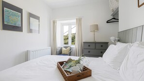 Relax in a stylish room with a large bed, dresser, and chair, featuring a beautiful bouquet and artwork.