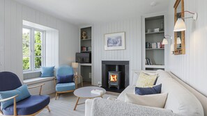 Cozy living room with a fireplace, comfortable seating, and a bookshelf.