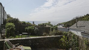 Enjoy a serene sea view from this residential setting, featuring a patio with a table and chairs.