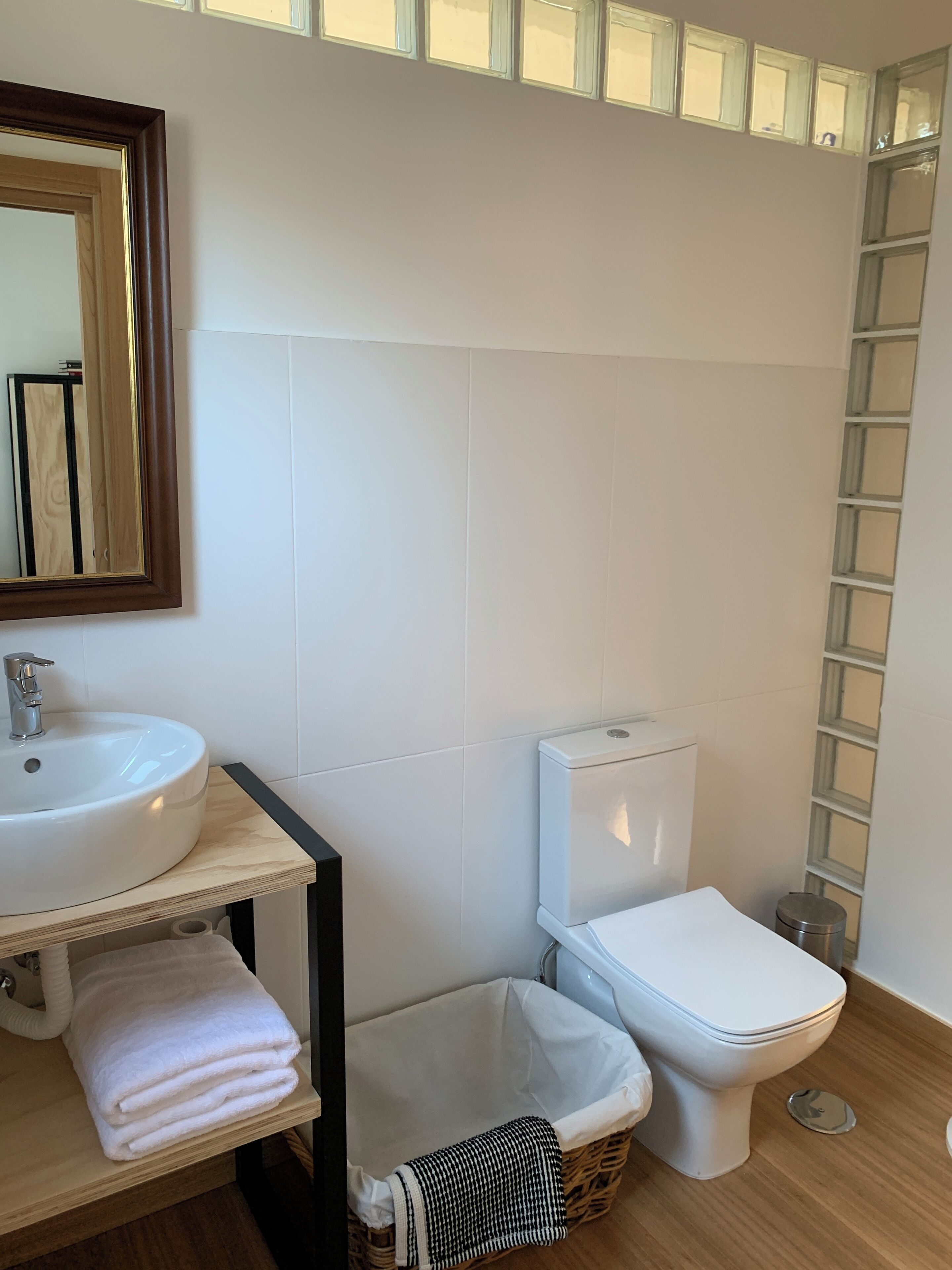 A bathroom with a white sink, toilet, and a small trash bin.