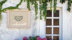 Ein weißes Gebäude mit einem Rahmen um das Schild "CASA LOURIDO" und einem Fenster mit satinierten Scheiben.