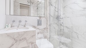 Un bagno moderno con un lavabo in marmo, una cabina doccia in vetro e uno specchio grande.