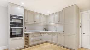 Una cucina moderna con mobili bianchi, forno integrato e pavimento in legno a parquet.