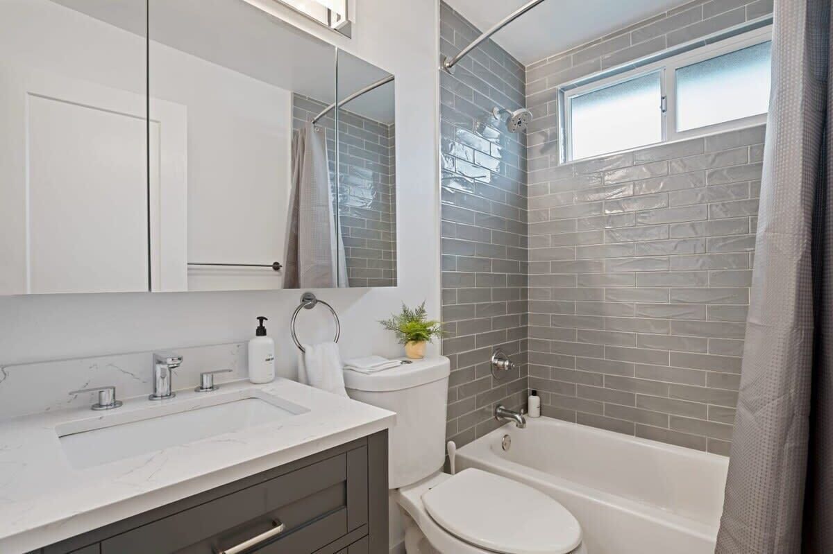 A modern bathroom with a white sink, a toilet, and a bathtub.