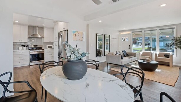 A modern kitchen with white cabinets, a large island with a marble top, and a ceiling fan. - @ Marbella Lane - 3BR Designer Home in Pacifica (Pacifica)