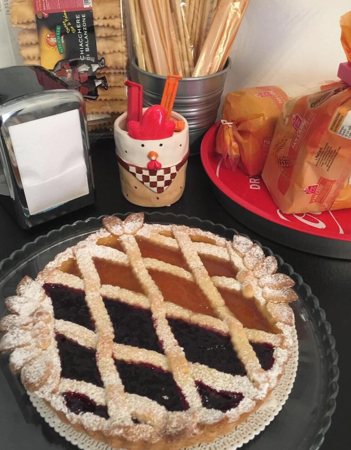 A dessert plate with a lattice-topped pie, a mug with a red and white design, and a glass with a white napkin.