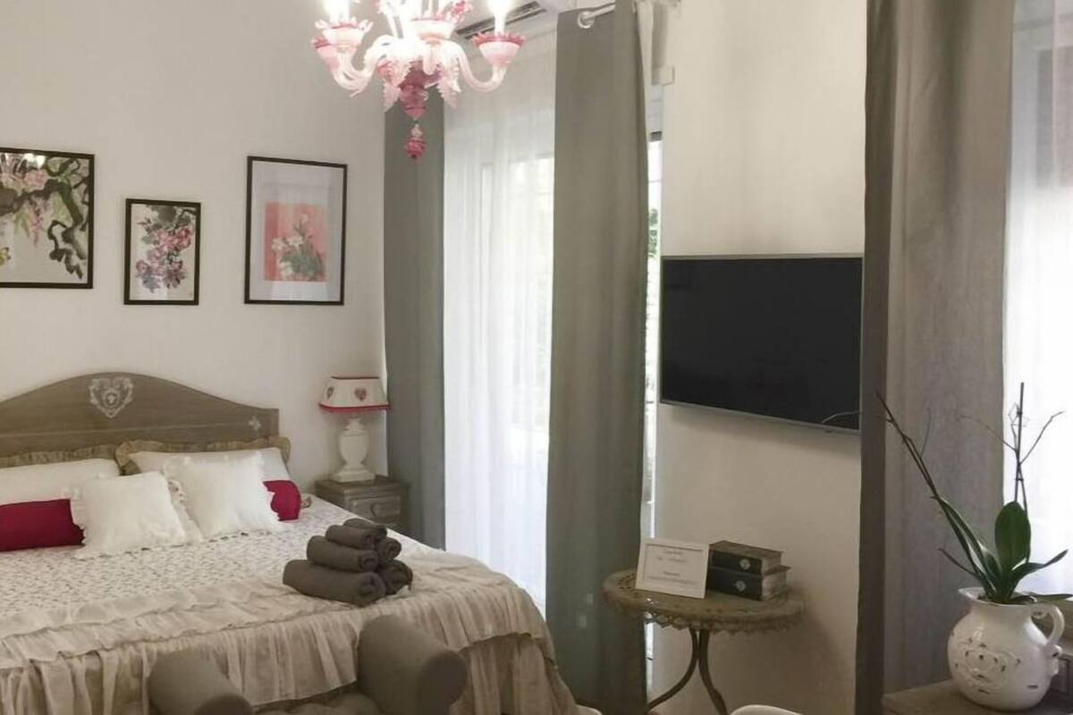 Ein ordentlich eingerichtetes Schlafzimmer mit einem Bett, einem Nachttisch, einem Fernseher und einer Topfpflanze.