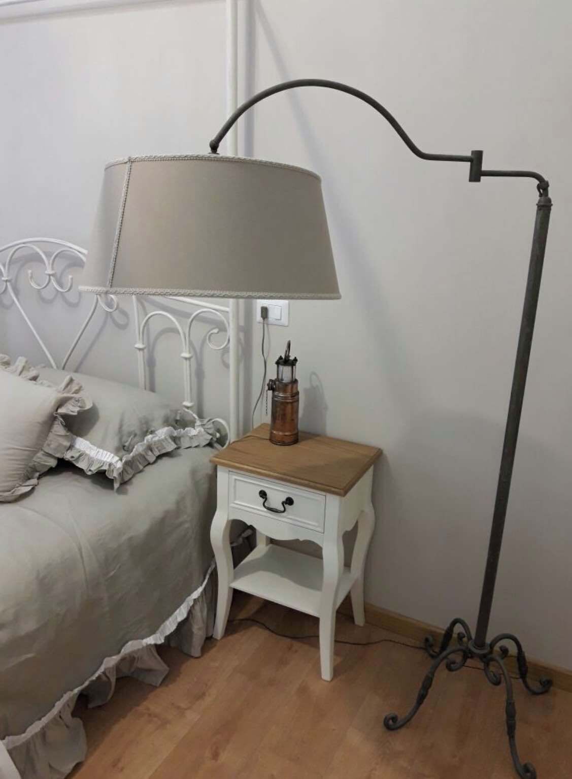 Une chambre à coucher avec un lit, une table de chevet avec une lampe et une lampe sur pied.