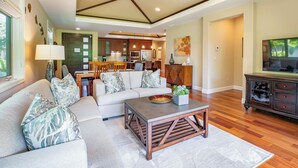 A spacious living area with a sofa, coffee table, and a TV stand.