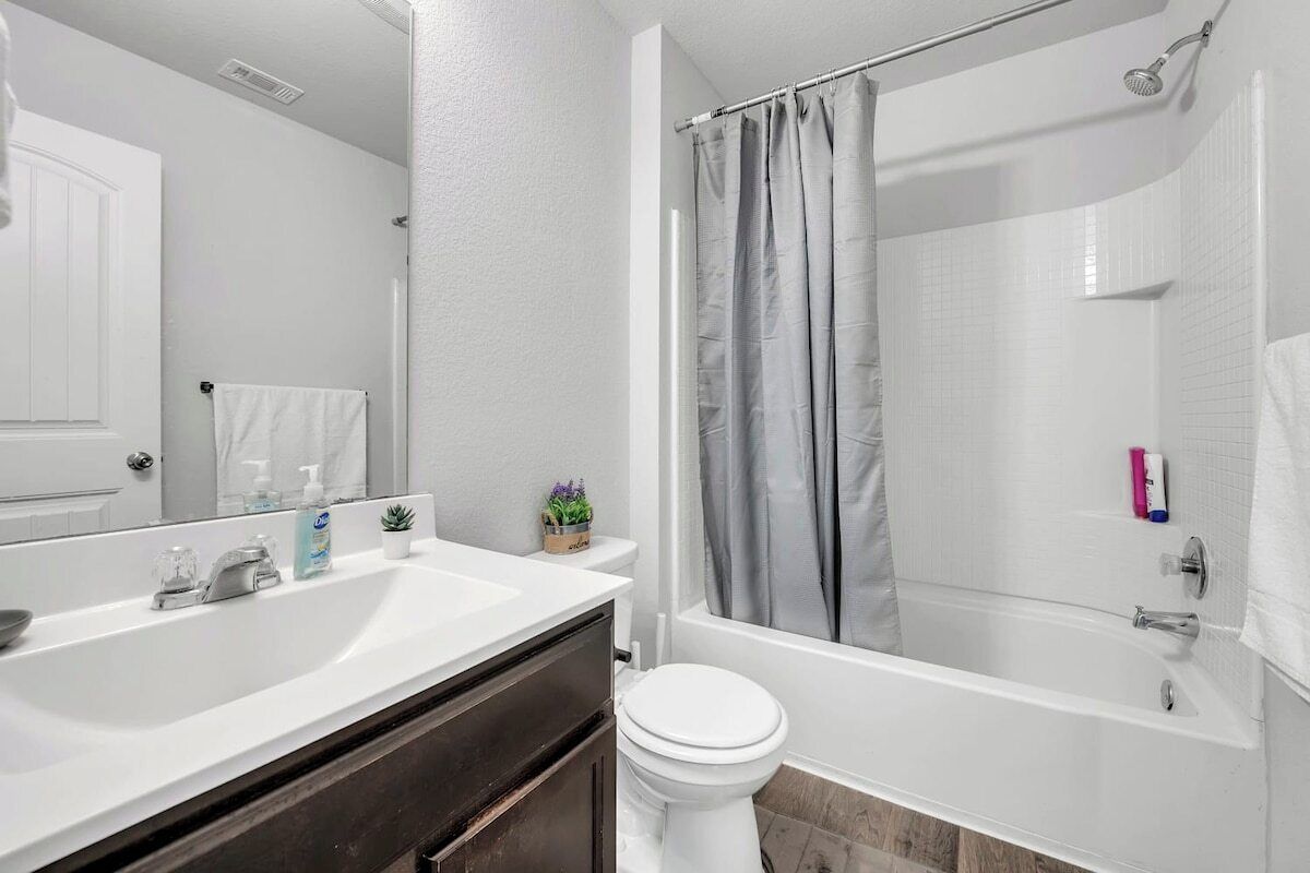 A bathroom with a white sink, a toilet, and a bathtub with a shower curtain.