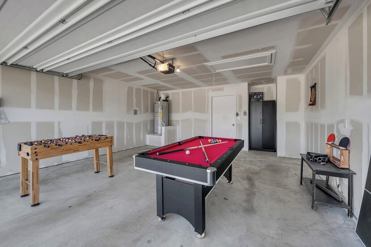 A room with a pool table, a foosball table, and a ping pong table.