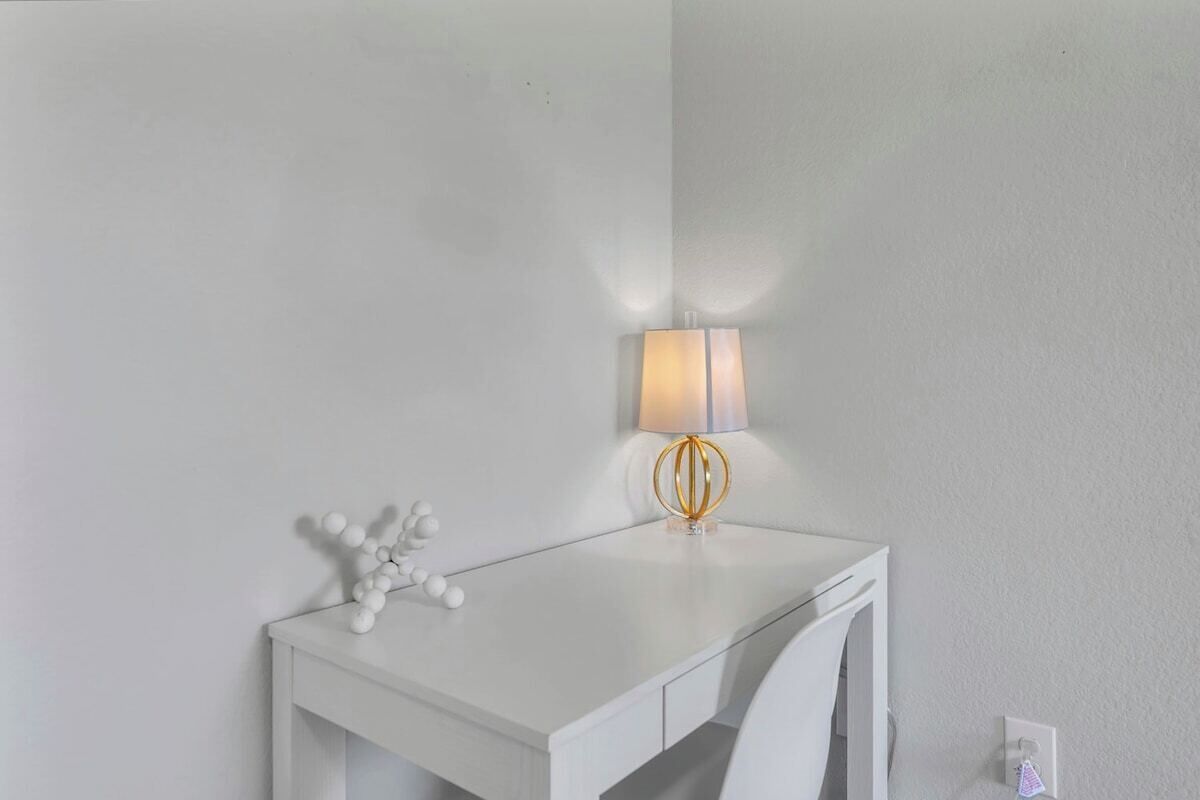 Un bureau blanc avec une lampe et un objet décoratif.