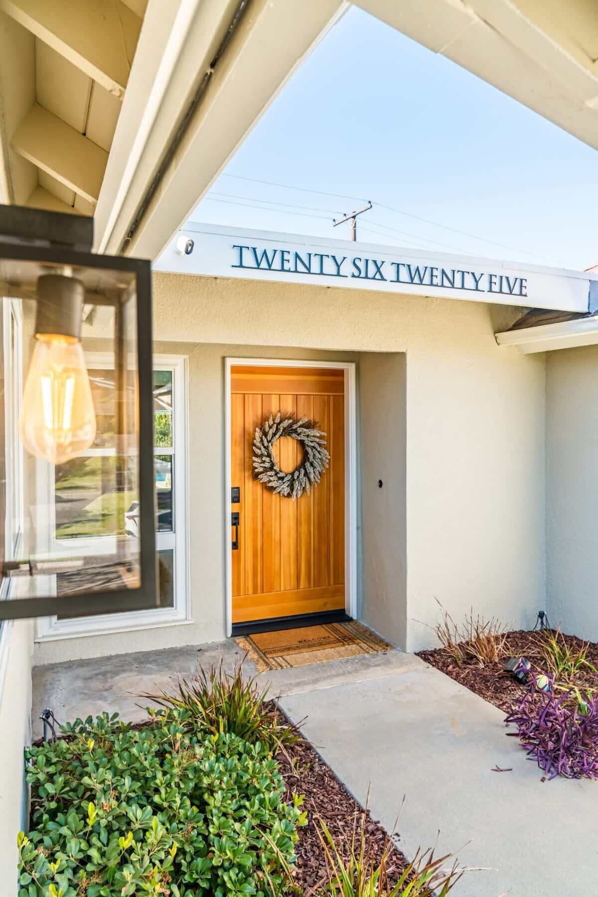 A modern house with a wooden front door, a welcome mat, and a wreath.