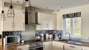 Eine moderne Küche mit weißen Schränken, einer Holz Arbeitsplatte, einem Einbauofen, einer Mikrowelle und einem Spülbecken.