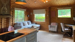 A cozy cabin interior with a wooden ceiling, a dining area with a wooden table, a sofa, and a chair.